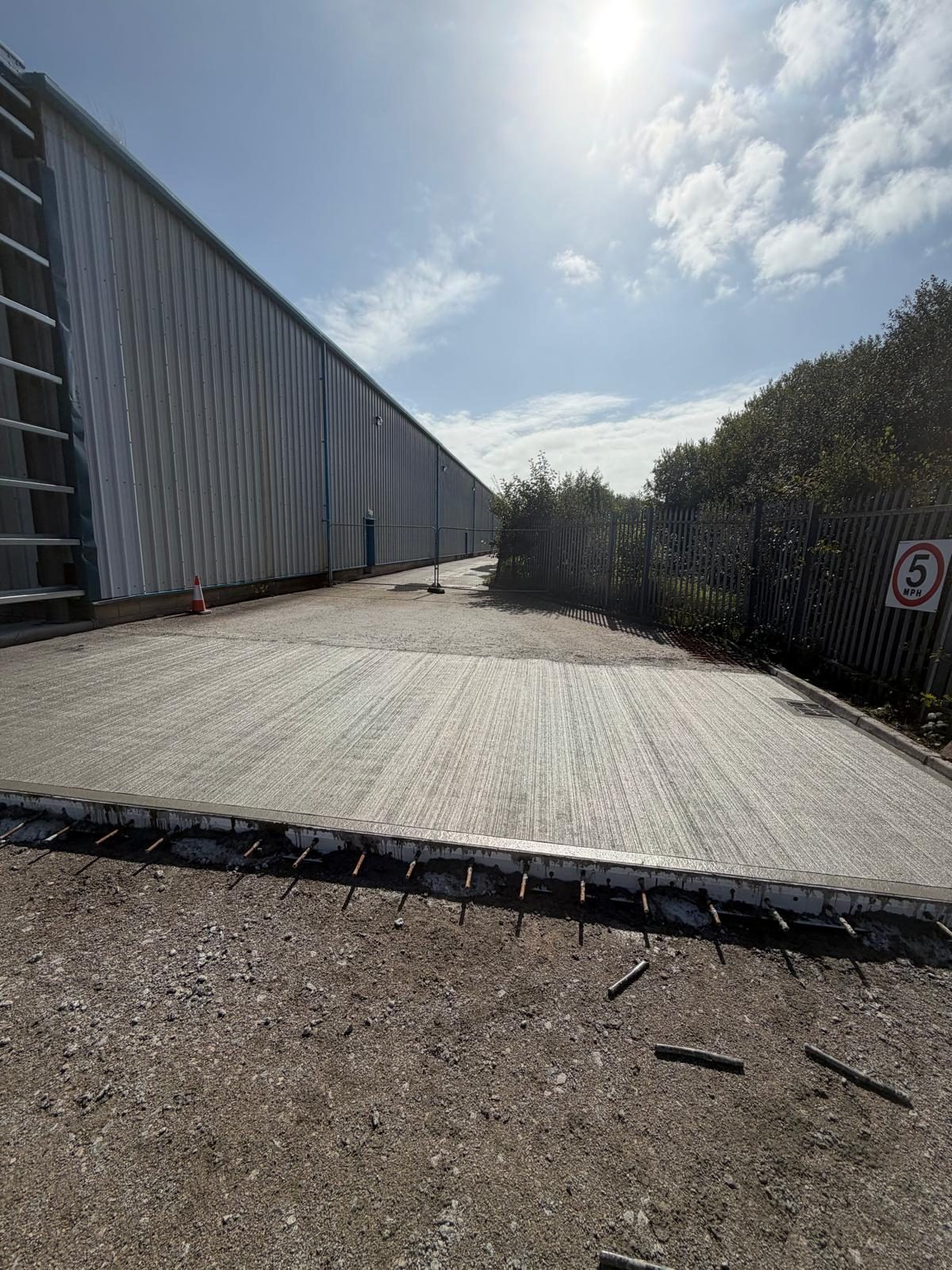 Brushed external concrete slab alongside a clad building