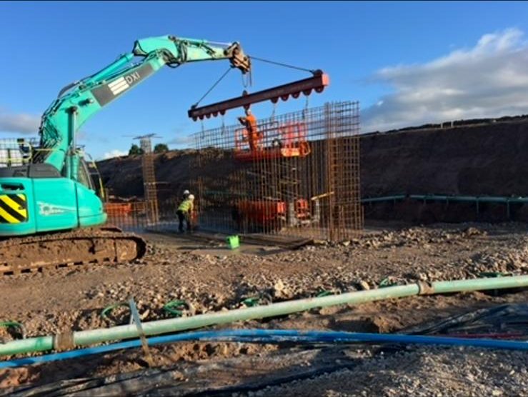 Excavator lifting a reinforcement cage into place